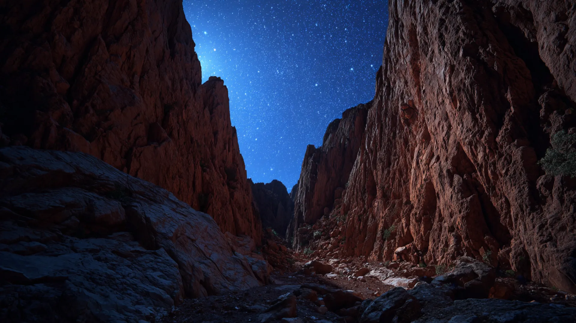 A narrow desert ravine at night under a star-filled sky, with distant silhouettes gathering in the valley and faint amber glow from pilgrim camps beyond
